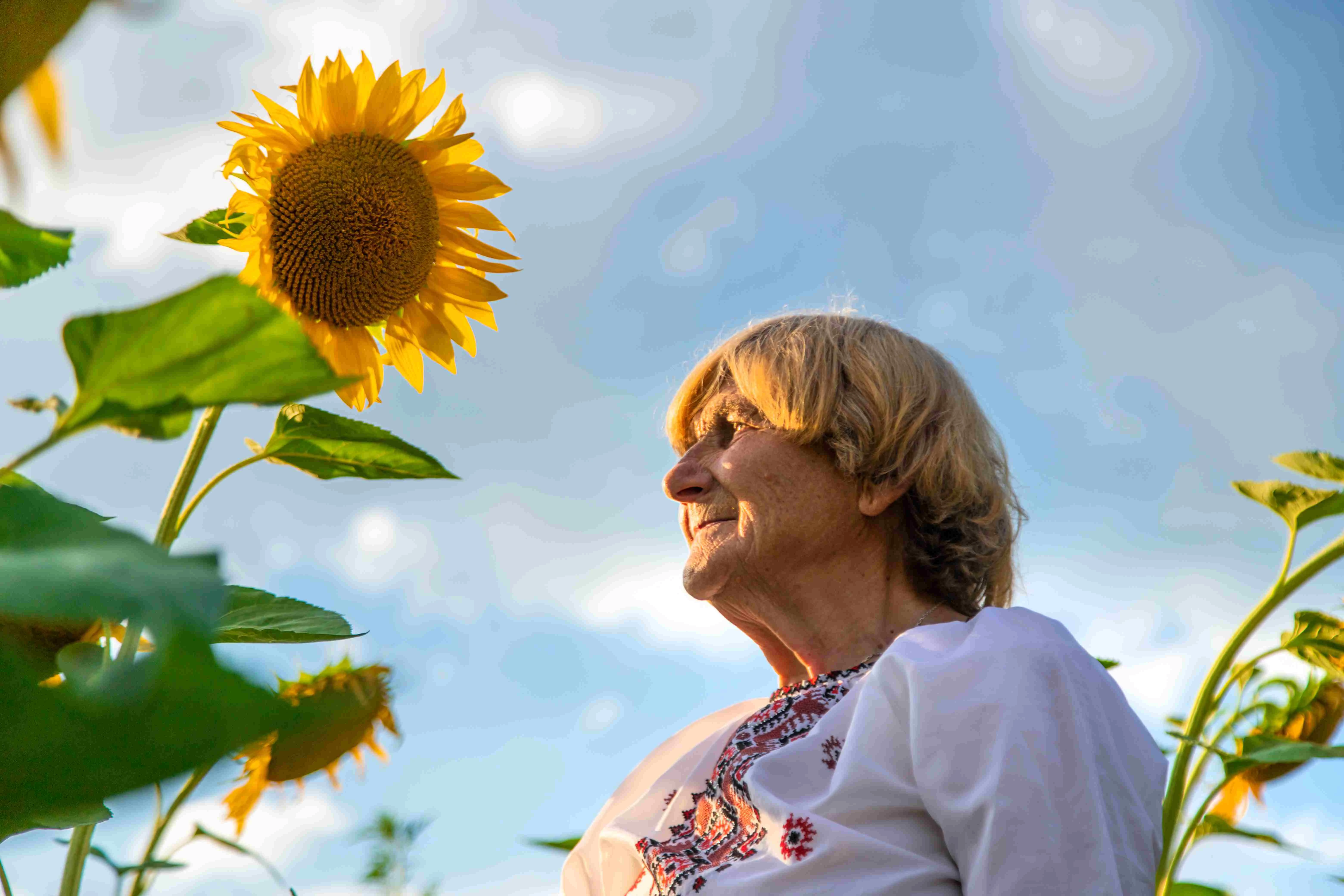 Vrouw met zonnebloem glimlacht – Symbool van hoop en veerkracht voor mensen met neurologische aandoeningen.